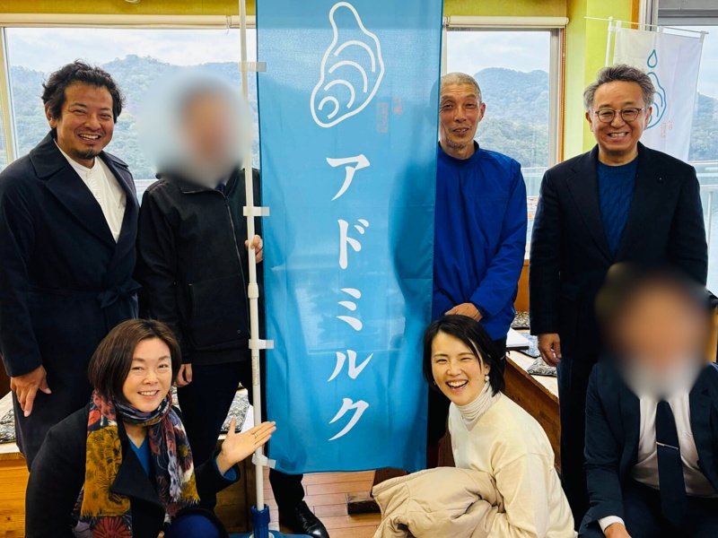 香川県安戸池での牡蠣養殖プロジェクトに参加した皆さんと、アドミルクの旗の前で記念撮影