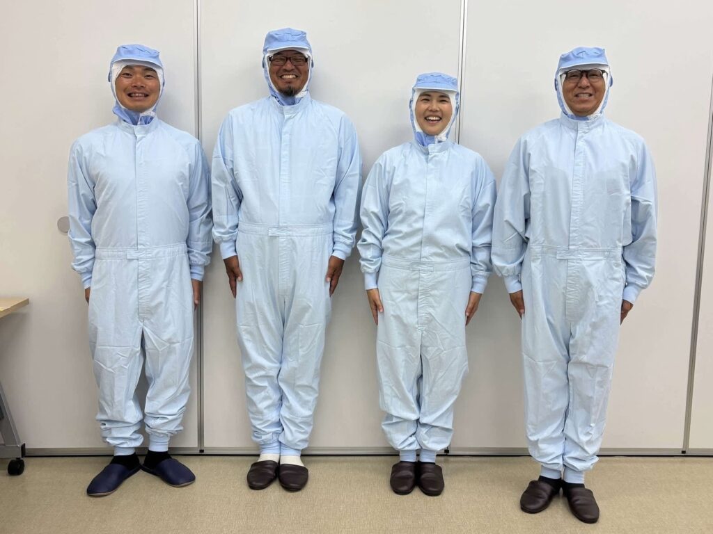 工場見学のため、クリーンルーム作業着を着た4人の集合写真